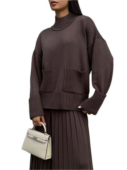 Person wearing a brown sweater holding a white handbag on a white background