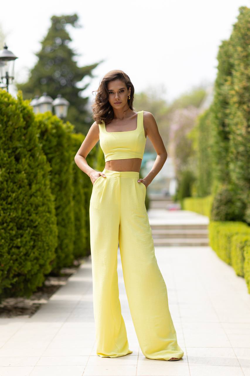 Woman in a yellow outfit standing on a path with greenery