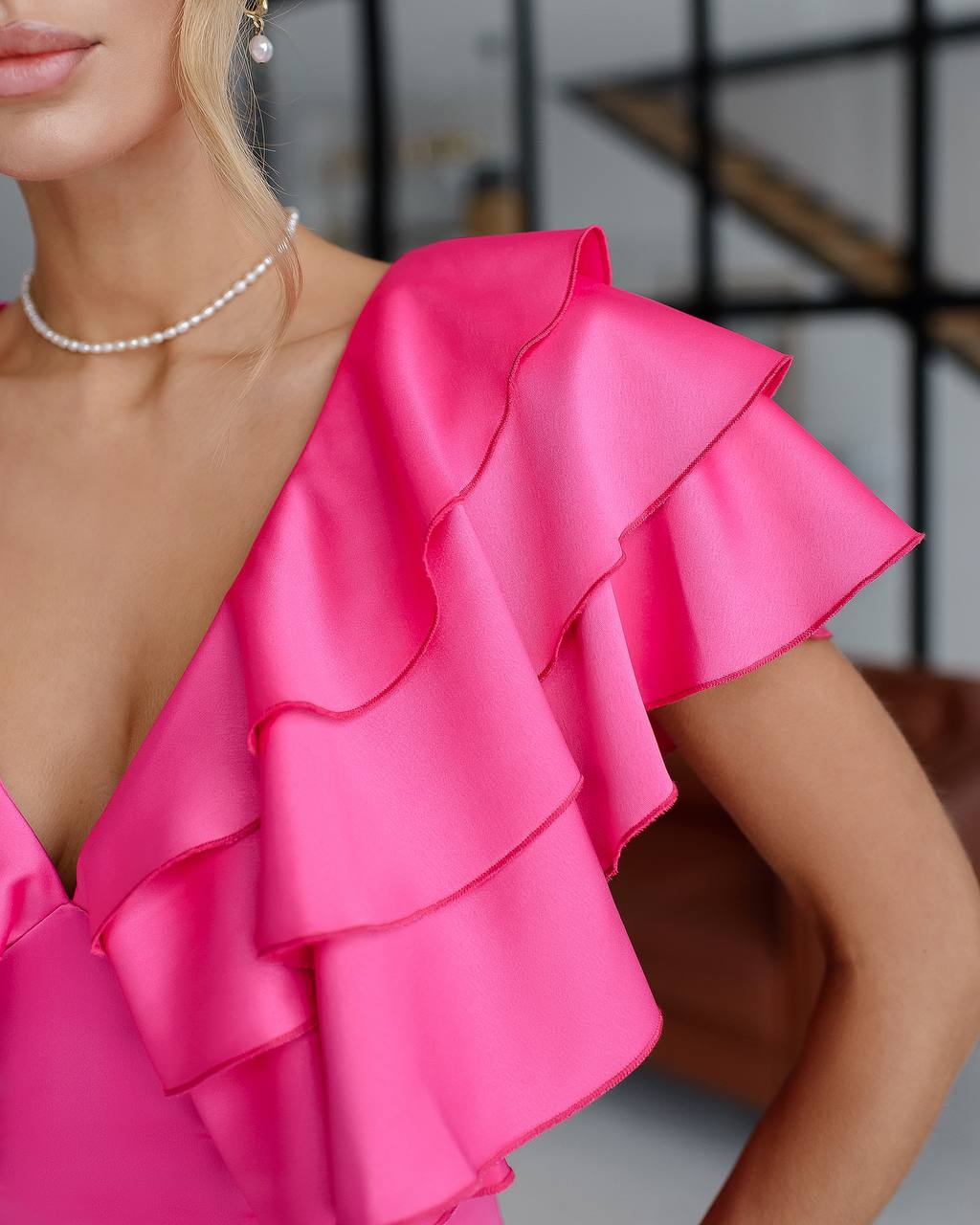 Close-up of a bright pink ruffled top worn by a person.