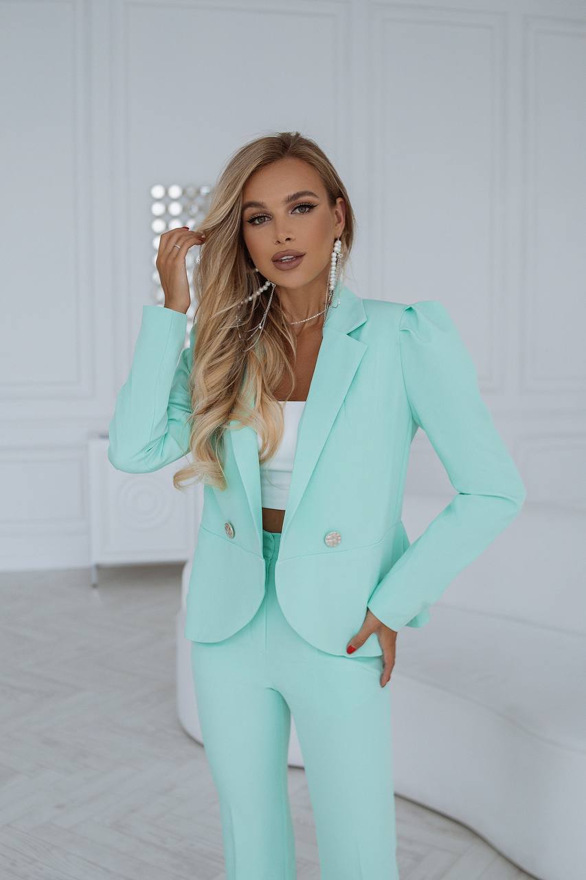 Woman wearing a mint green suit in a minimalistic setting