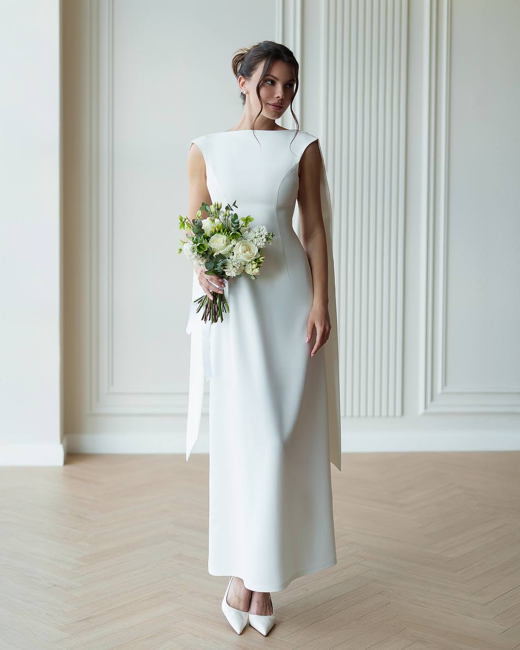 Woman in a white dress holding a bouquet of flowers in a minimalistic setting