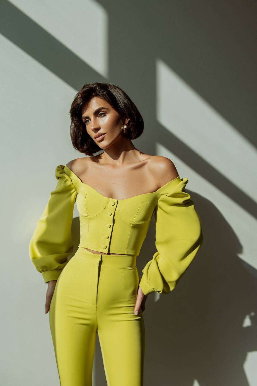 Woman wearing a bright yellow outfit against a light background