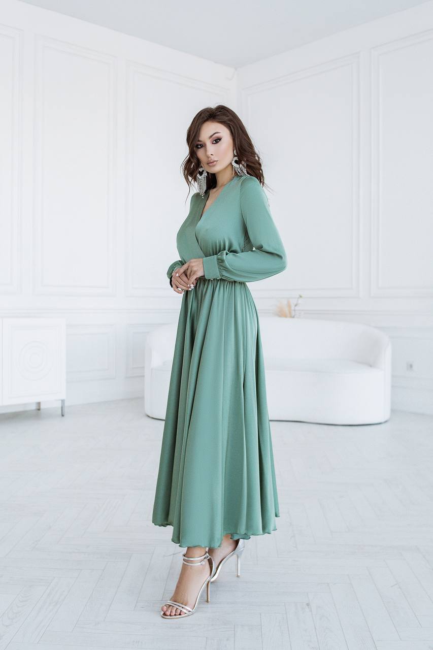 Woman wearing a long green dress in a minimalistic room.
