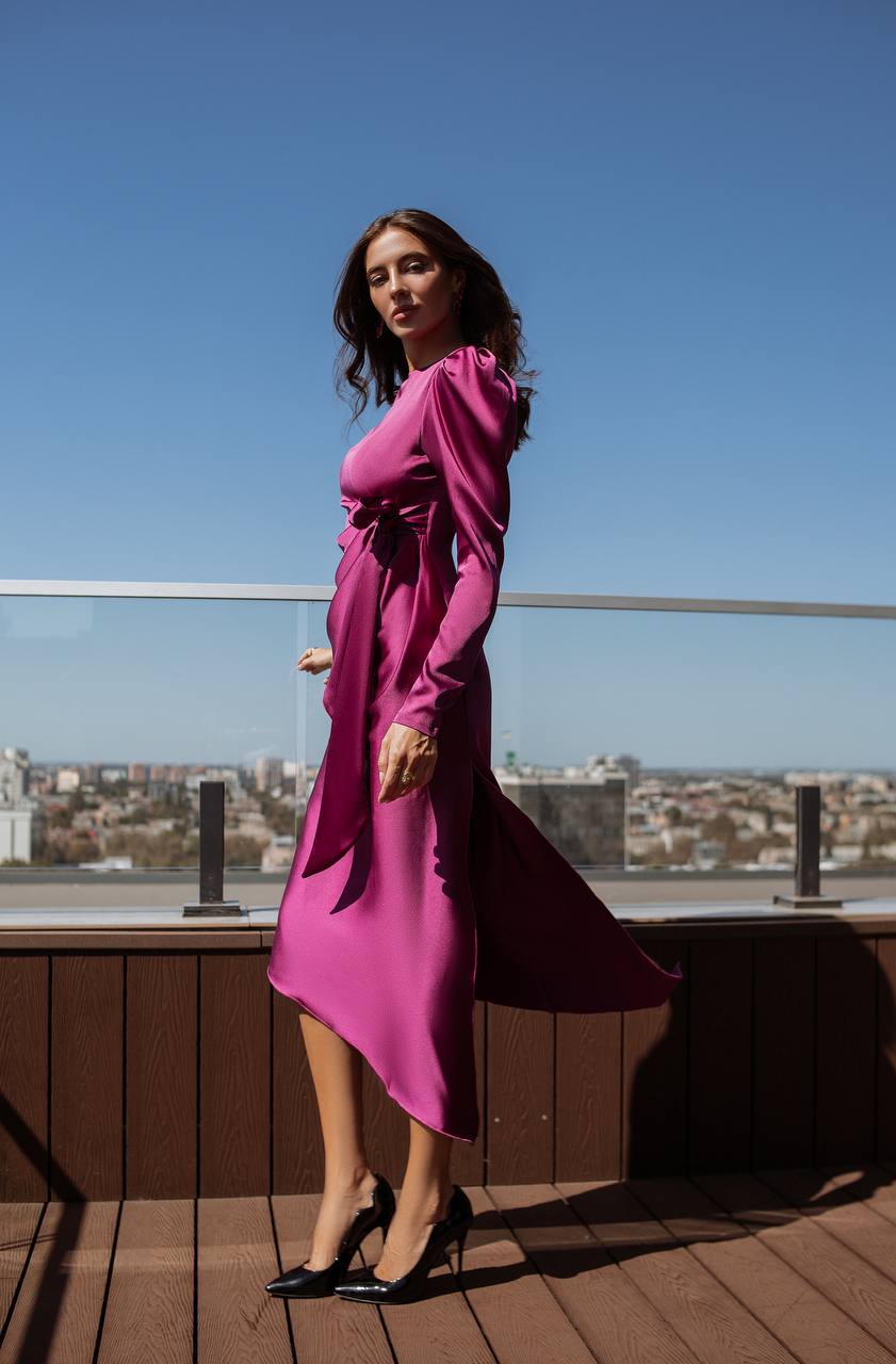 Woman in a pink dress standing on a rooftop with a cityscape in the background