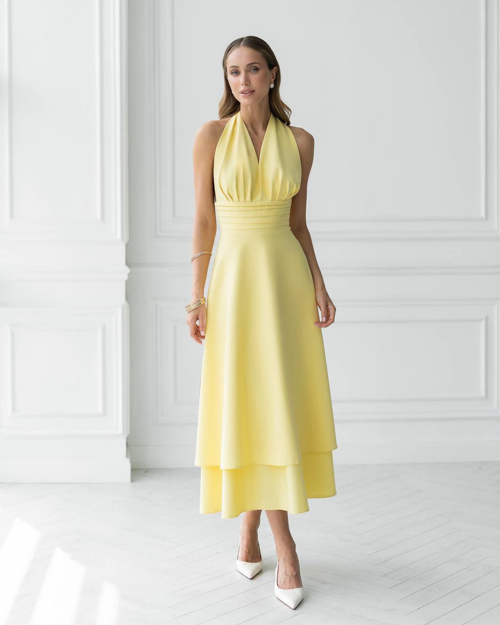 Woman wearing a yellow dress against a white wall