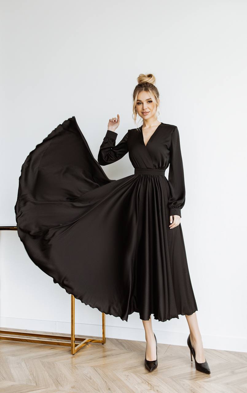 Woman wearing a black dress with a flowing skirt against a white background