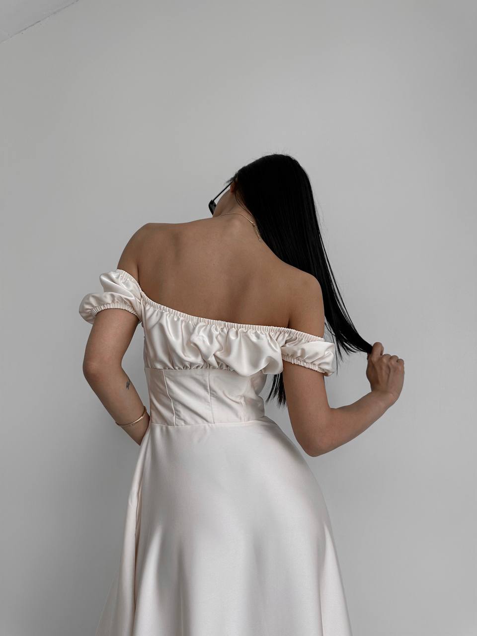 Woman wearing a white off-shoulder dress against a plain background