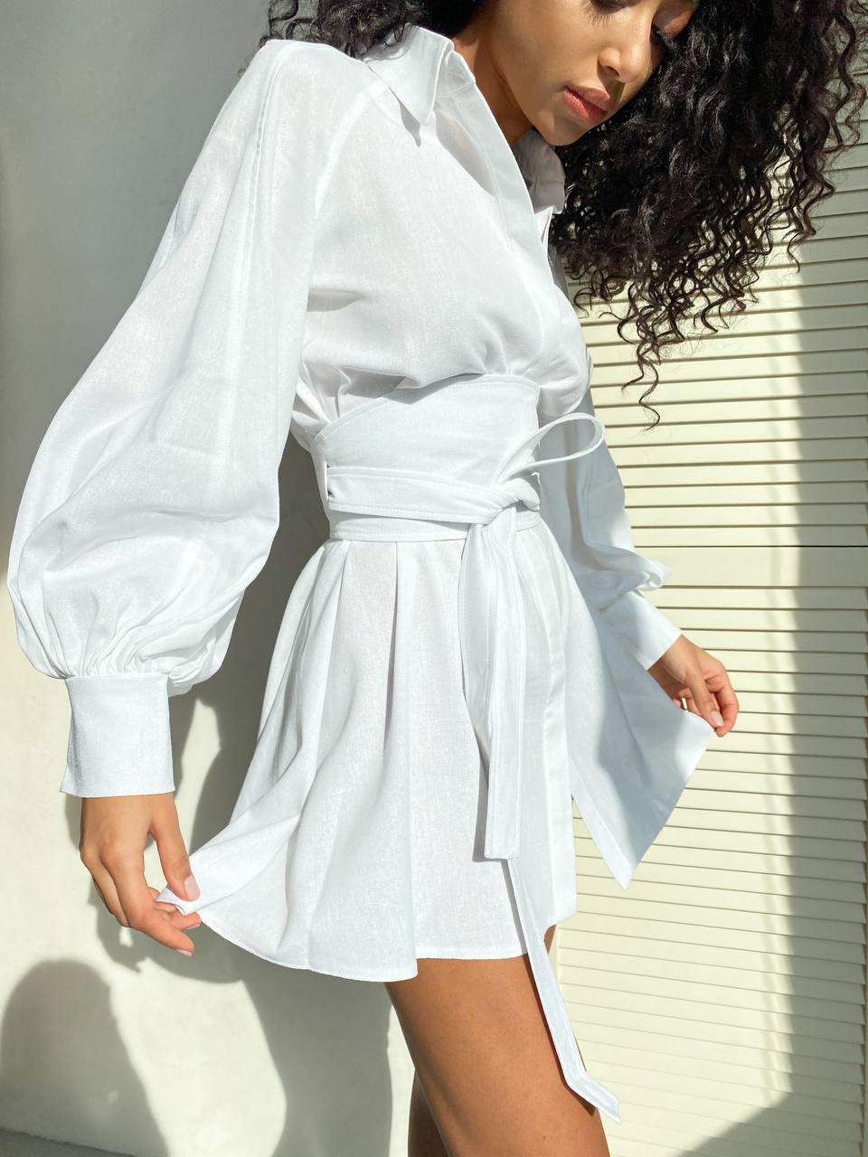 Woman wearing a white dress with puffed sleeves against a neutral background