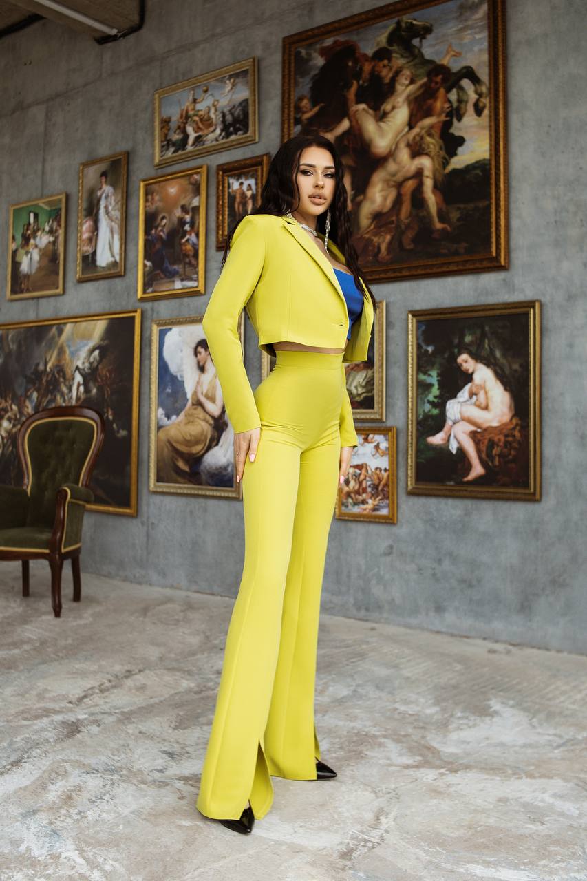 Woman in a yellow suit standing in a room with classical art paintings on the wall.
