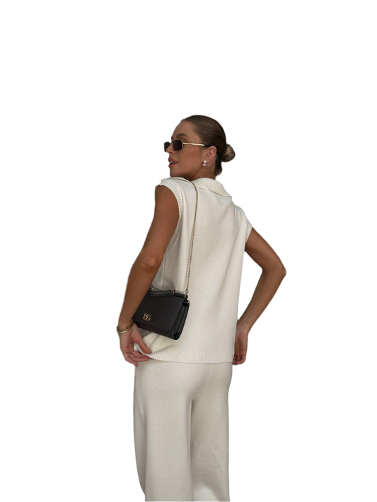 Woman in a white outfit with a black handbag on a white background