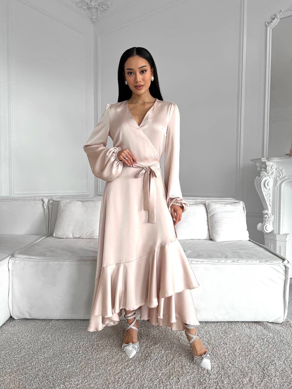 Woman wearing a pink satin dress in a room with white walls and furniture.