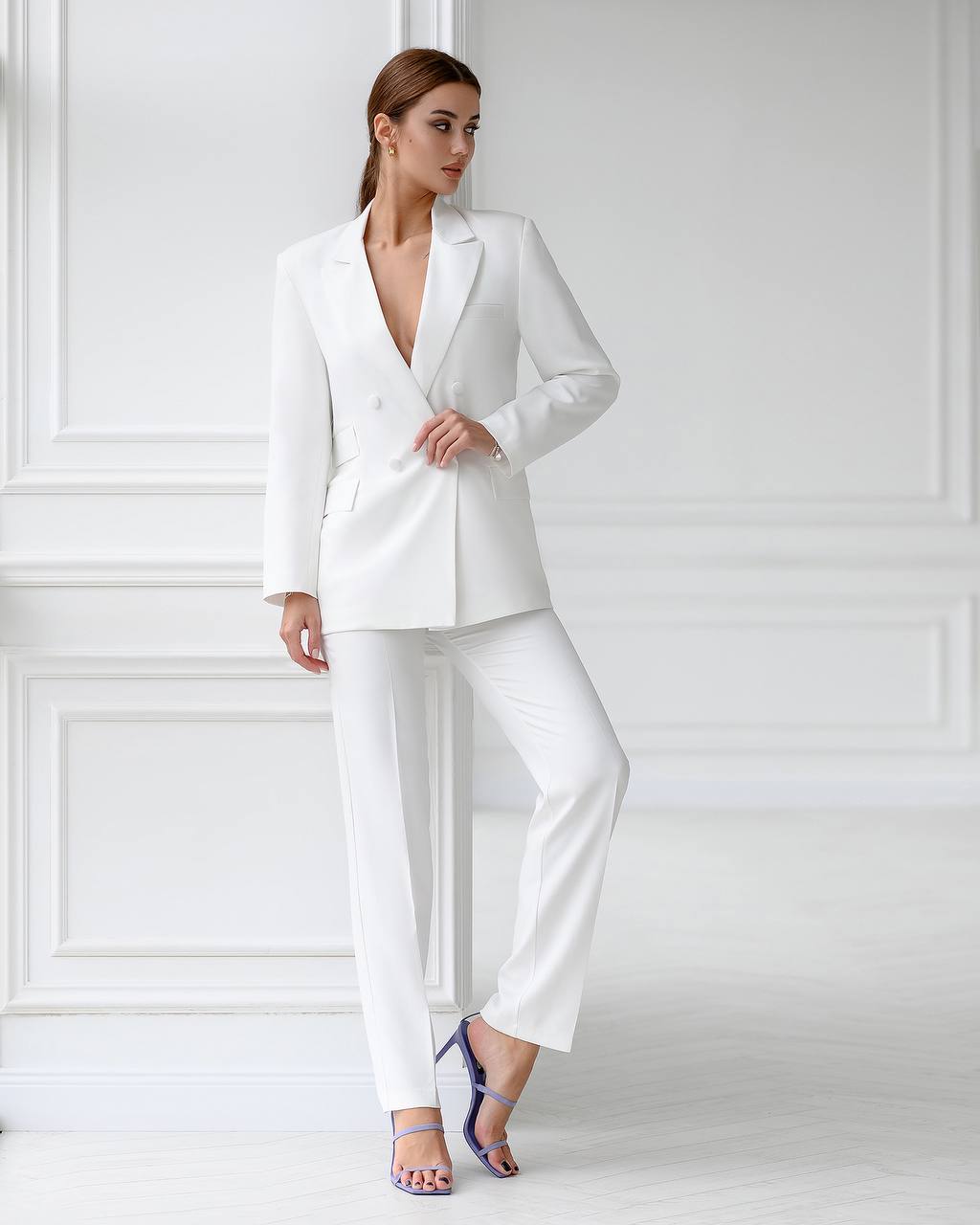 Woman wearing a white suit against a white wall