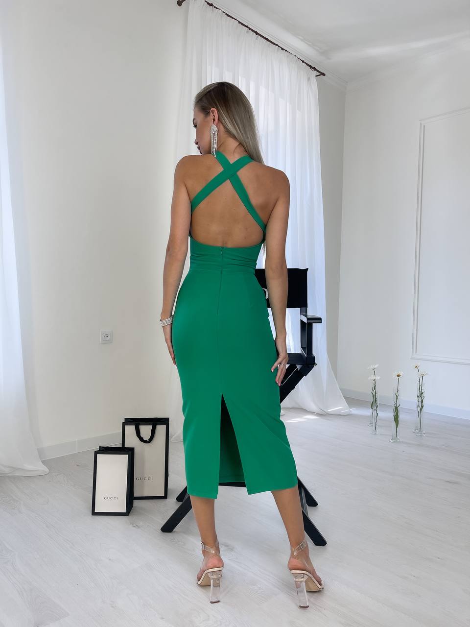 Woman wearing a green dress with a backless design in a minimalistic room.