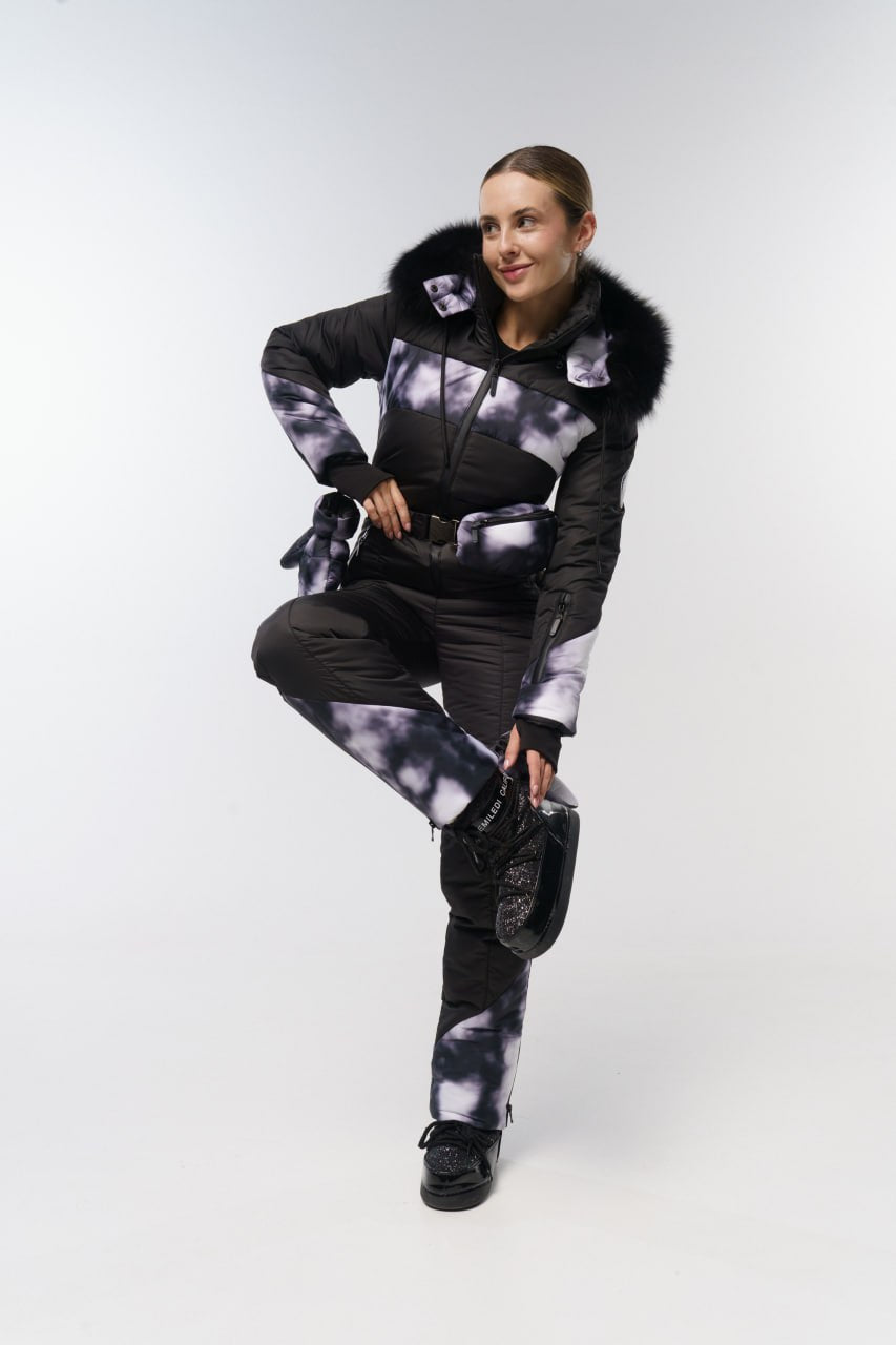 Person wearing a black and white patterned outfit with fur-lined hood on a white background