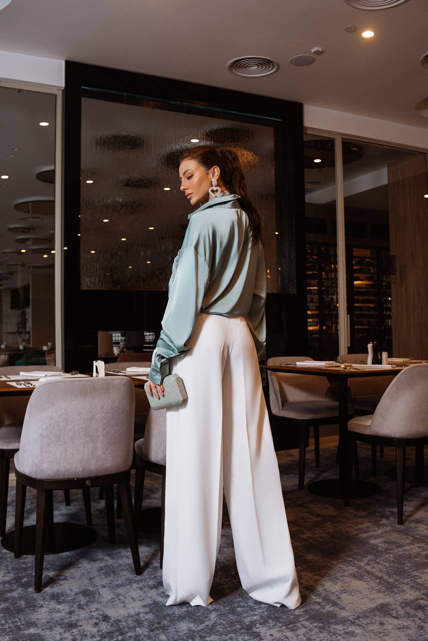 Woman standing in a modern restaurant with tables and chairs.