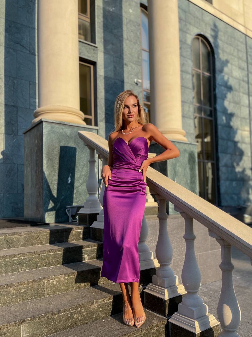 Woman in a purple dress standing on steps in front of a classical building
