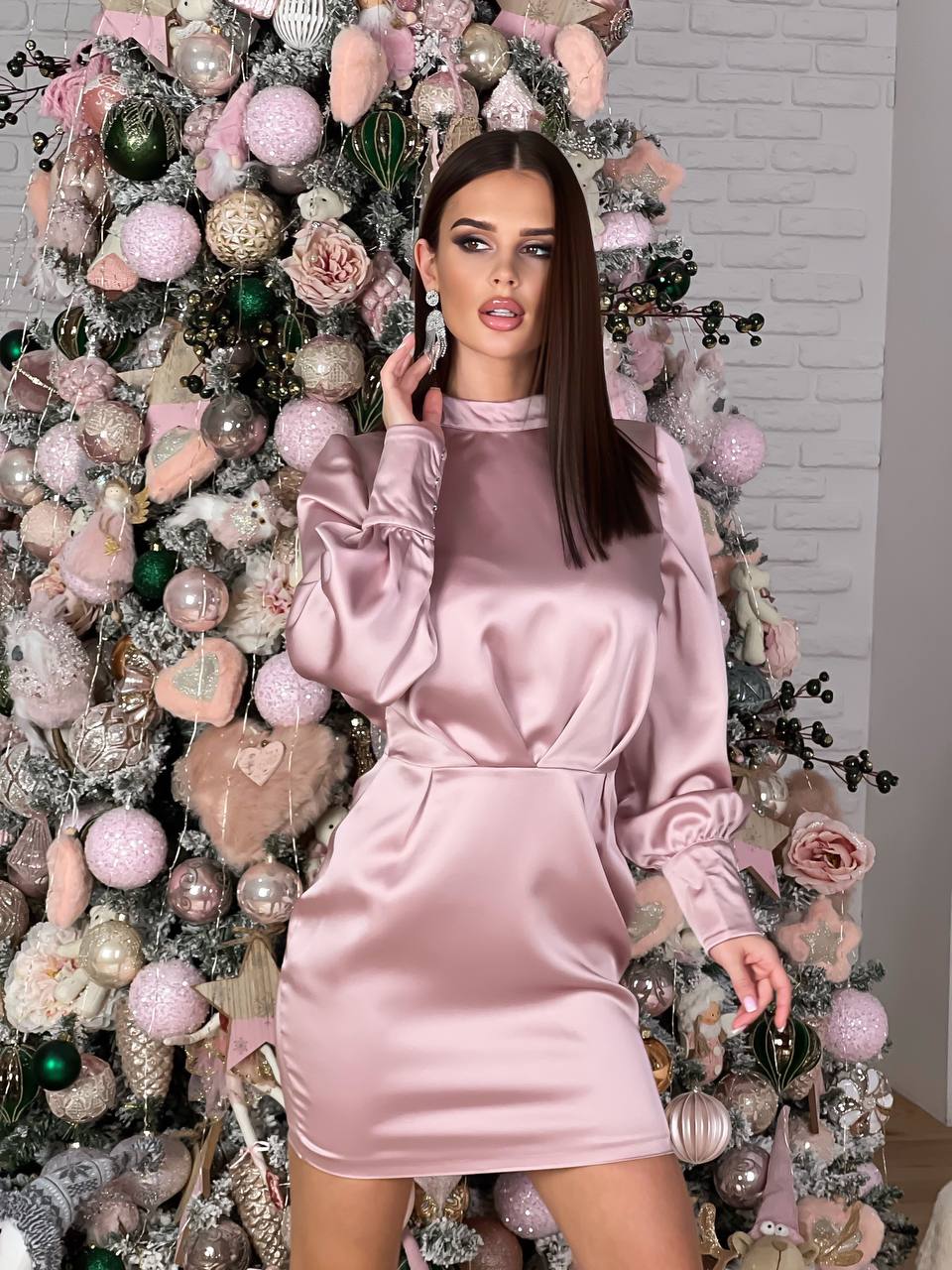 Woman in a pink dress standing in front of a decorated Christmas tree.