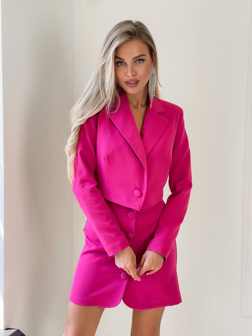 Woman wearing a bright pink suit against a plain background