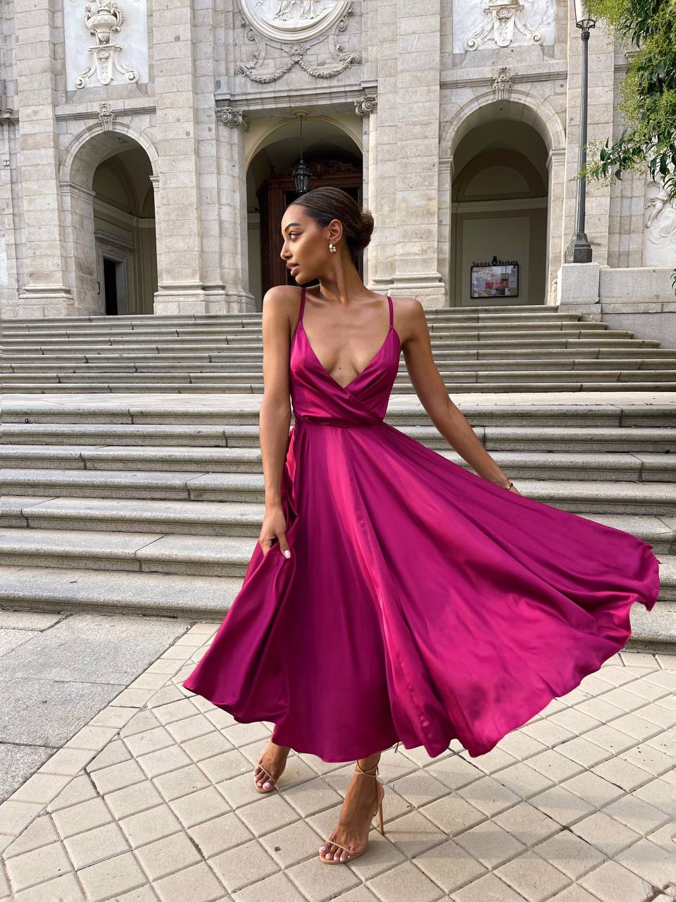 Woman in a pink dress standing in front of an architectural building
