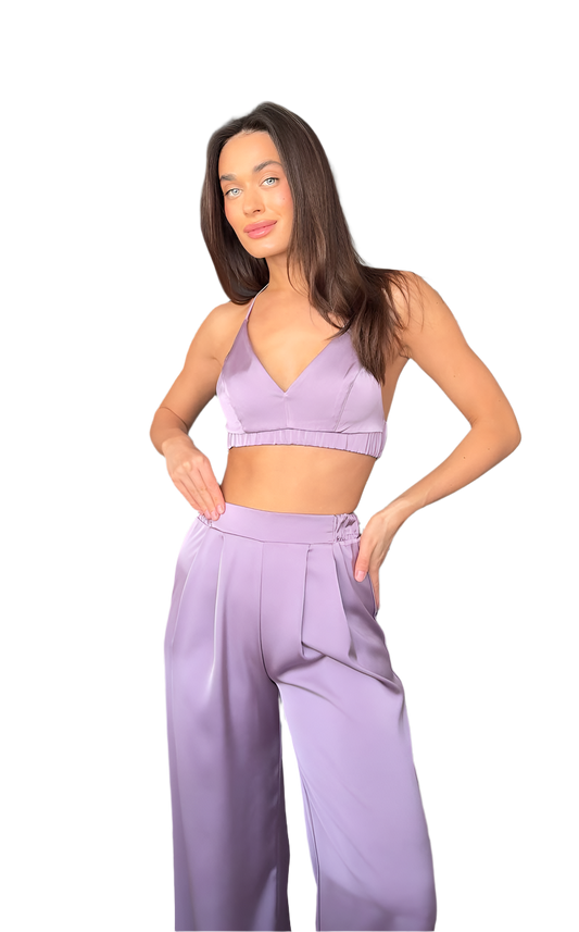 Woman wearing a matching lavender sports bra and wide-leg pants on a white background