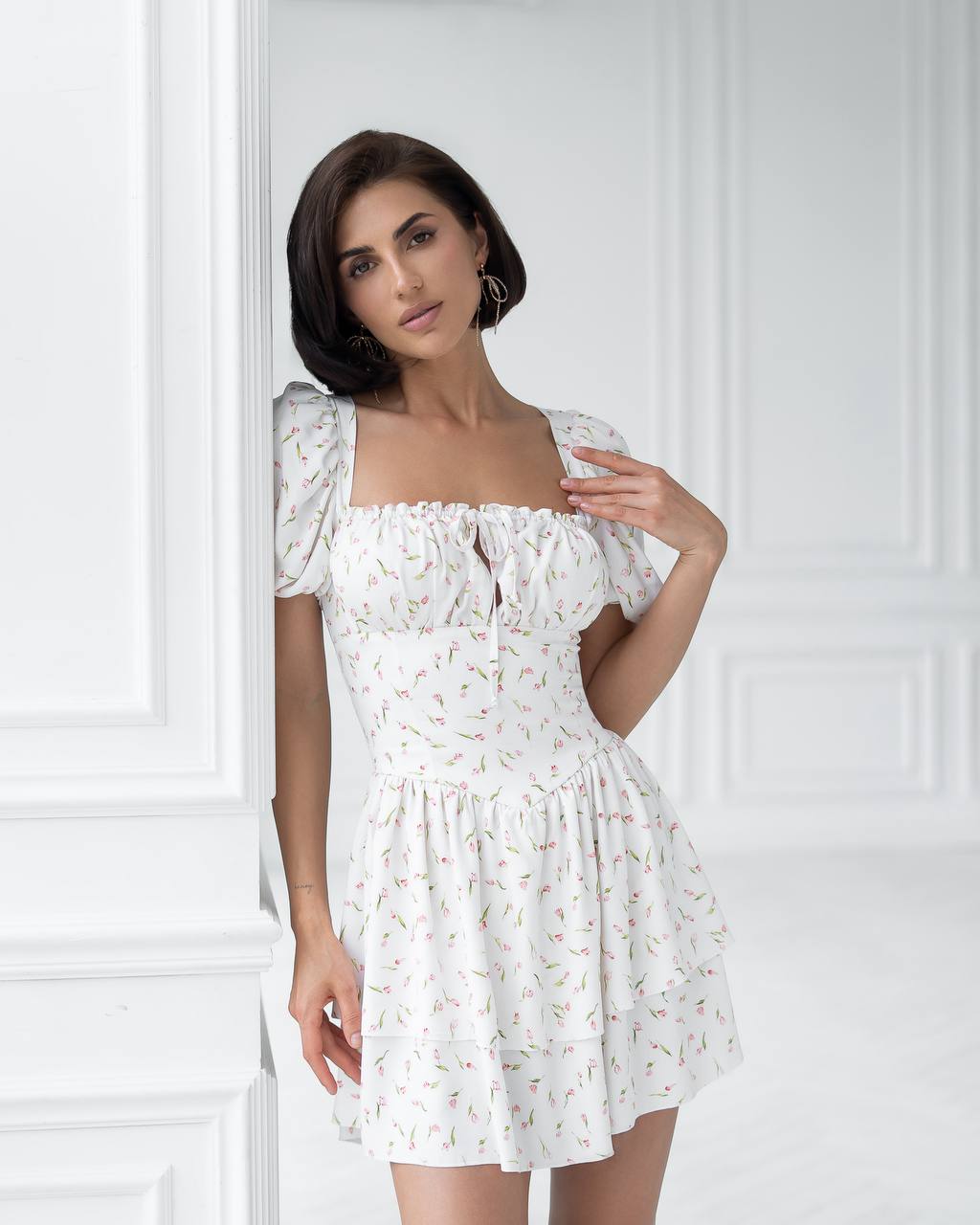 Woman wearing a white floral dress against a white background