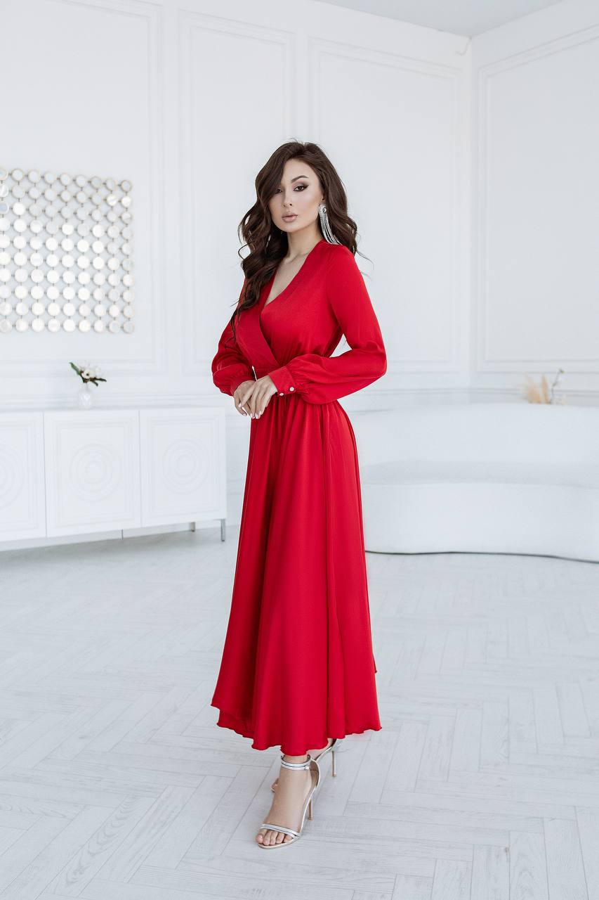 Woman in a red dress standing in a minimalistic room with white walls and floor.