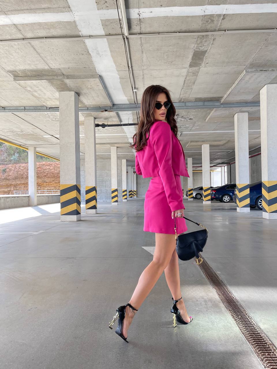 Woman in a pink outfit walking in an underground parking lot.