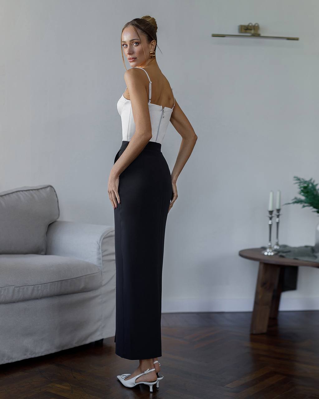 Woman in a black and white dress standing in a living room.