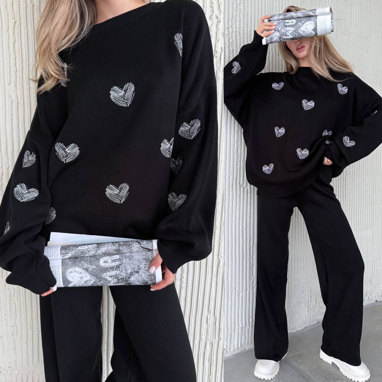 Person wearing a black sweater with heart patterns and holding a silver clutch.