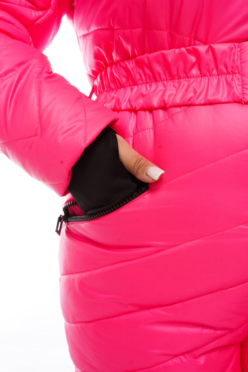 Close-up of a bright pink puffer jacket with a hand reaching into a black pocket.