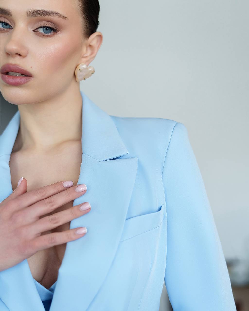 Woman wearing a light blue blazer with a neutral background