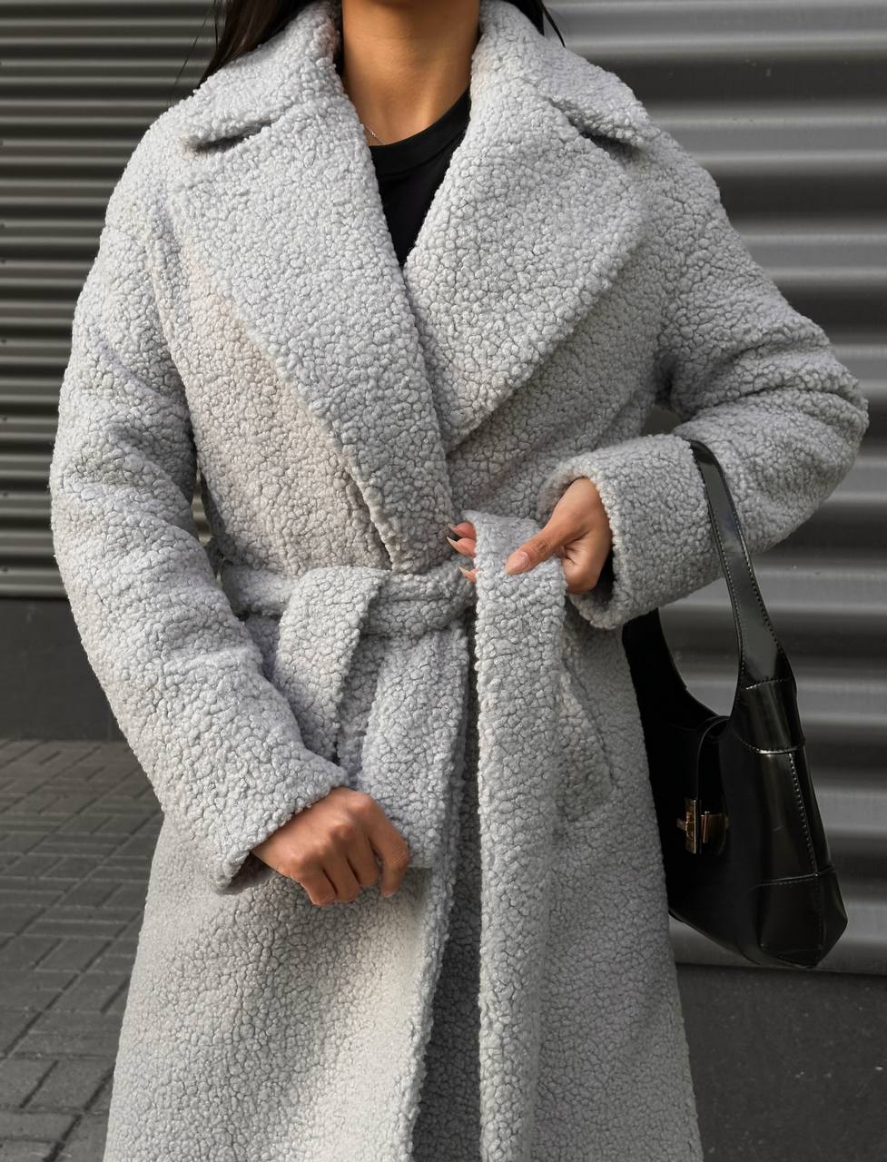 Person wearing a gray teddy coat with a blurred background