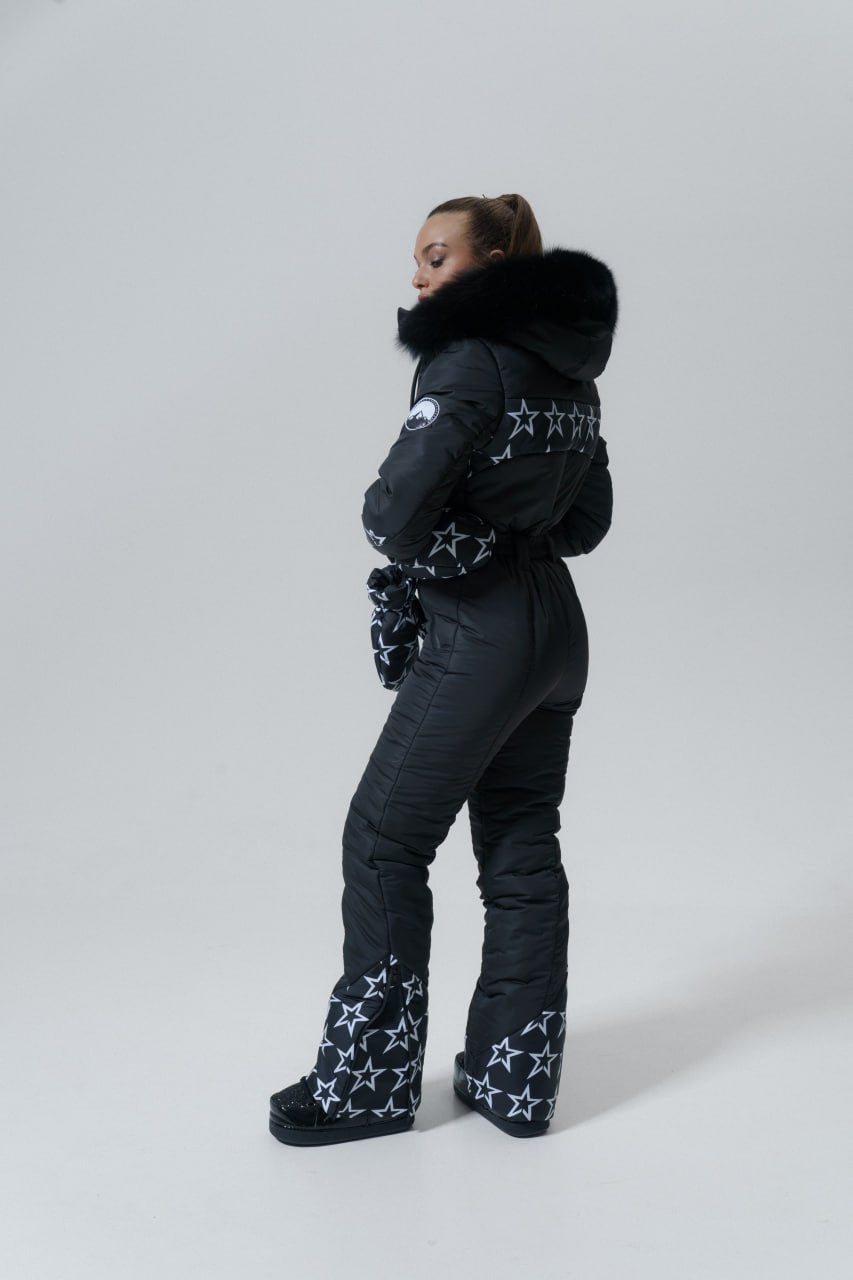 Person wearing a black puffer jacket, pants, and boots with star patterns on a white background
