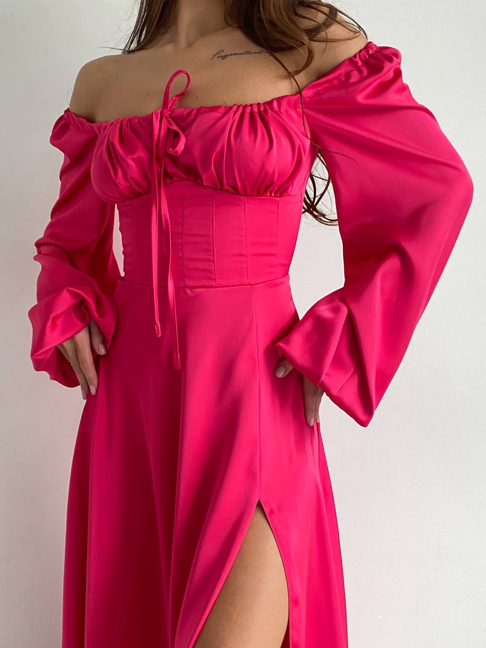 Pink off-shoulder dress with long sleeves on a plain background