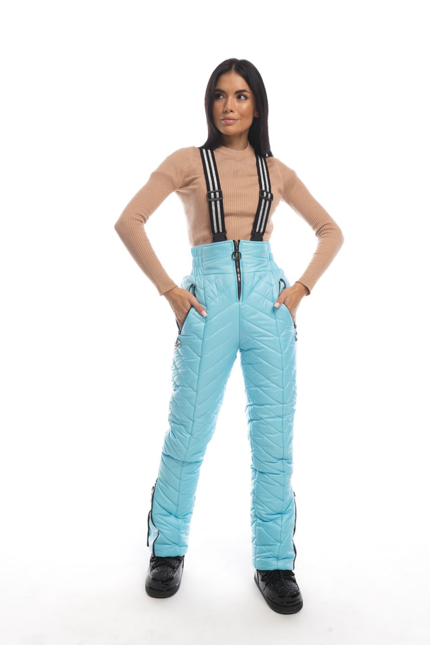 Person wearing light blue snow pants with suspenders on a white background