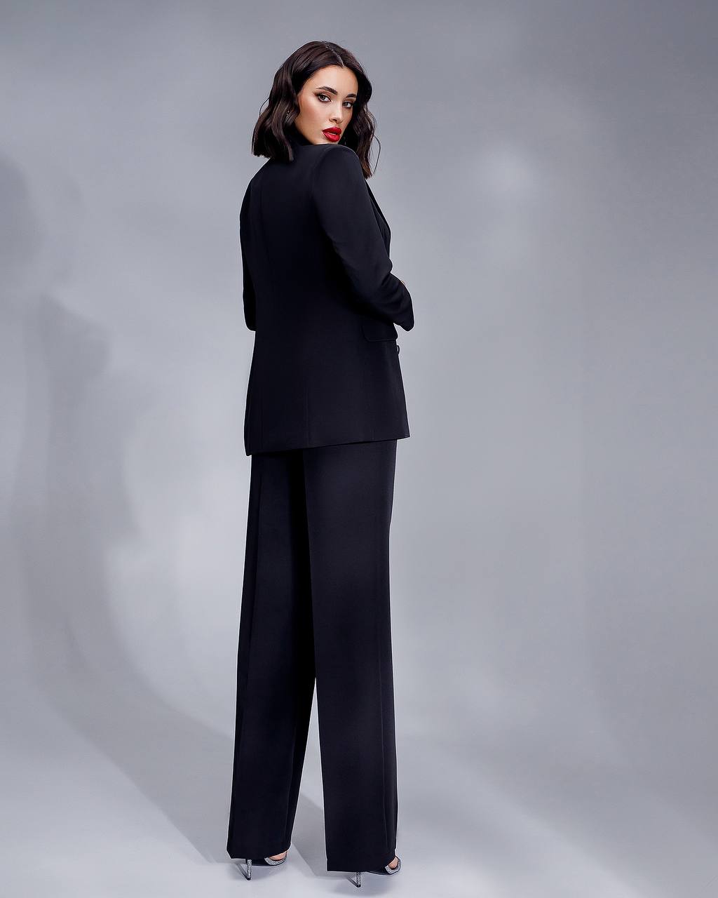 Woman wearing a black suit against a gray background