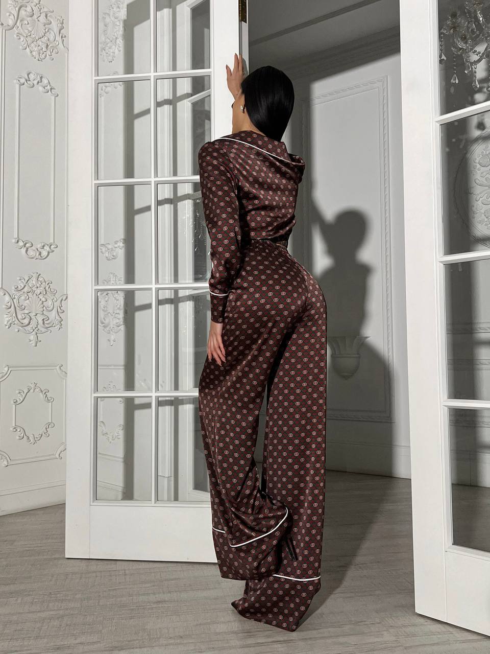 Person wearing a patterned pajama set standing in a doorway.