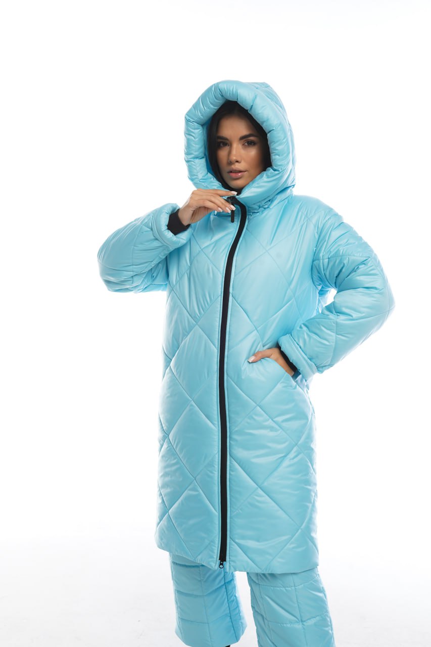 Person wearing a light blue quilted jacket with a hood on a white background