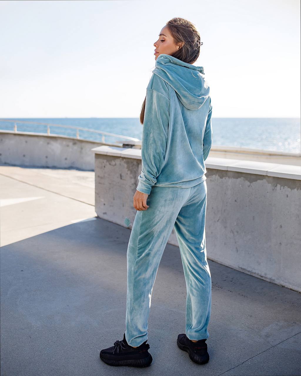 Person wearing a light blue tracksuit standing on a rooftop with ocean view