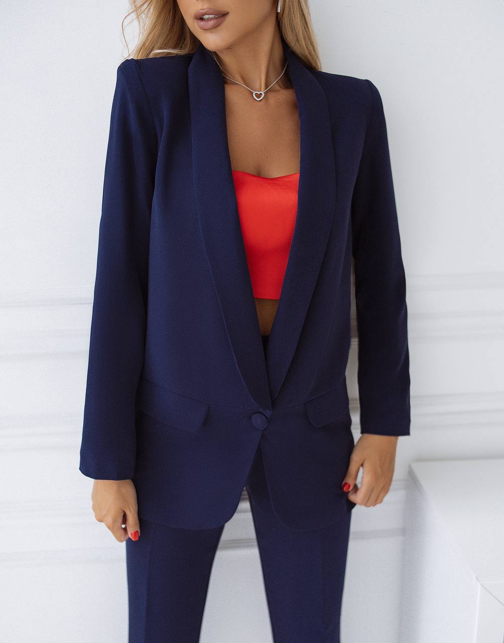 Person wearing a navy blue suit with a red top against a white background