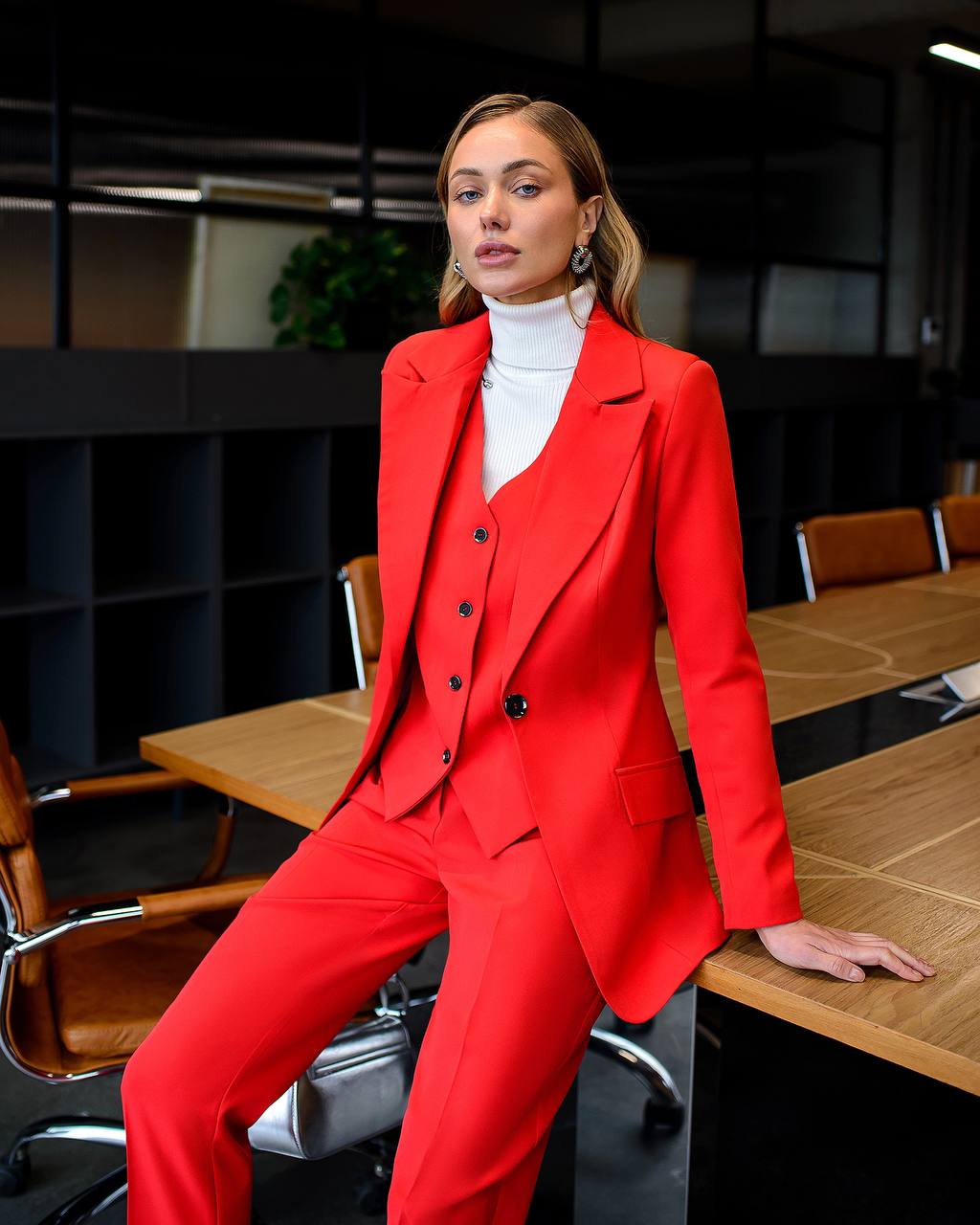 Woman in a red suit sitting at a desk in an office setting