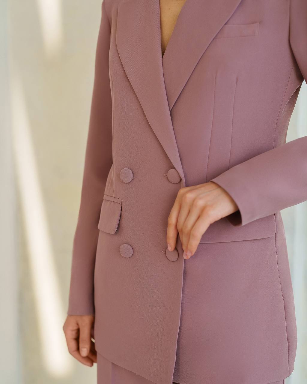 Mauve suit jacket with buttons on a neutral background