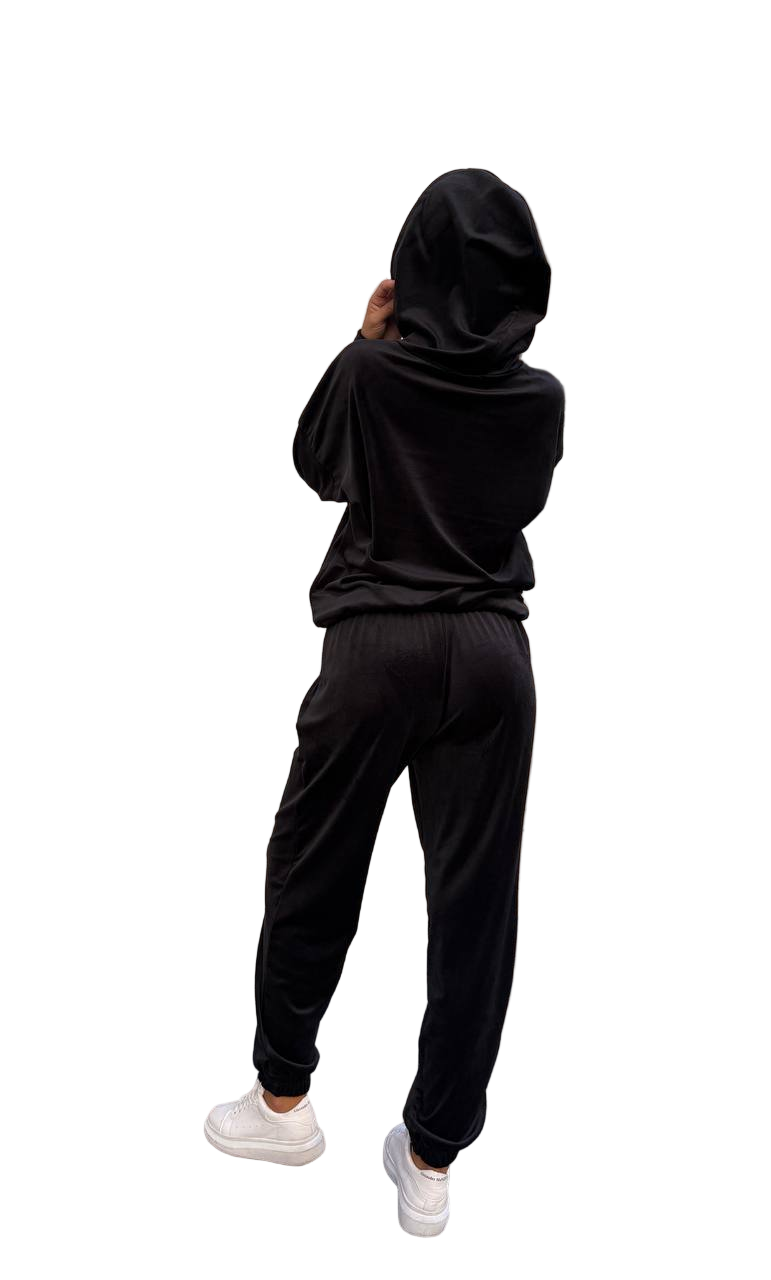 Person wearing a black hoodie and pants on a white background