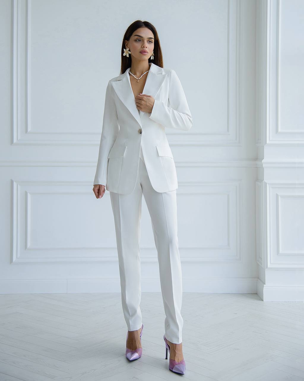 Woman wearing a white suit in a minimalistic room