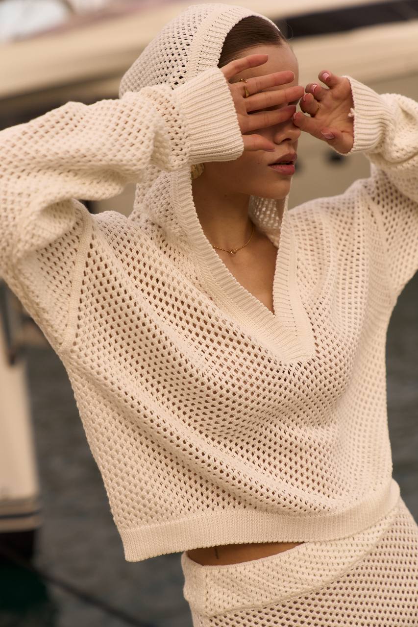 Person wearing a beige knit sweater with a blurred background