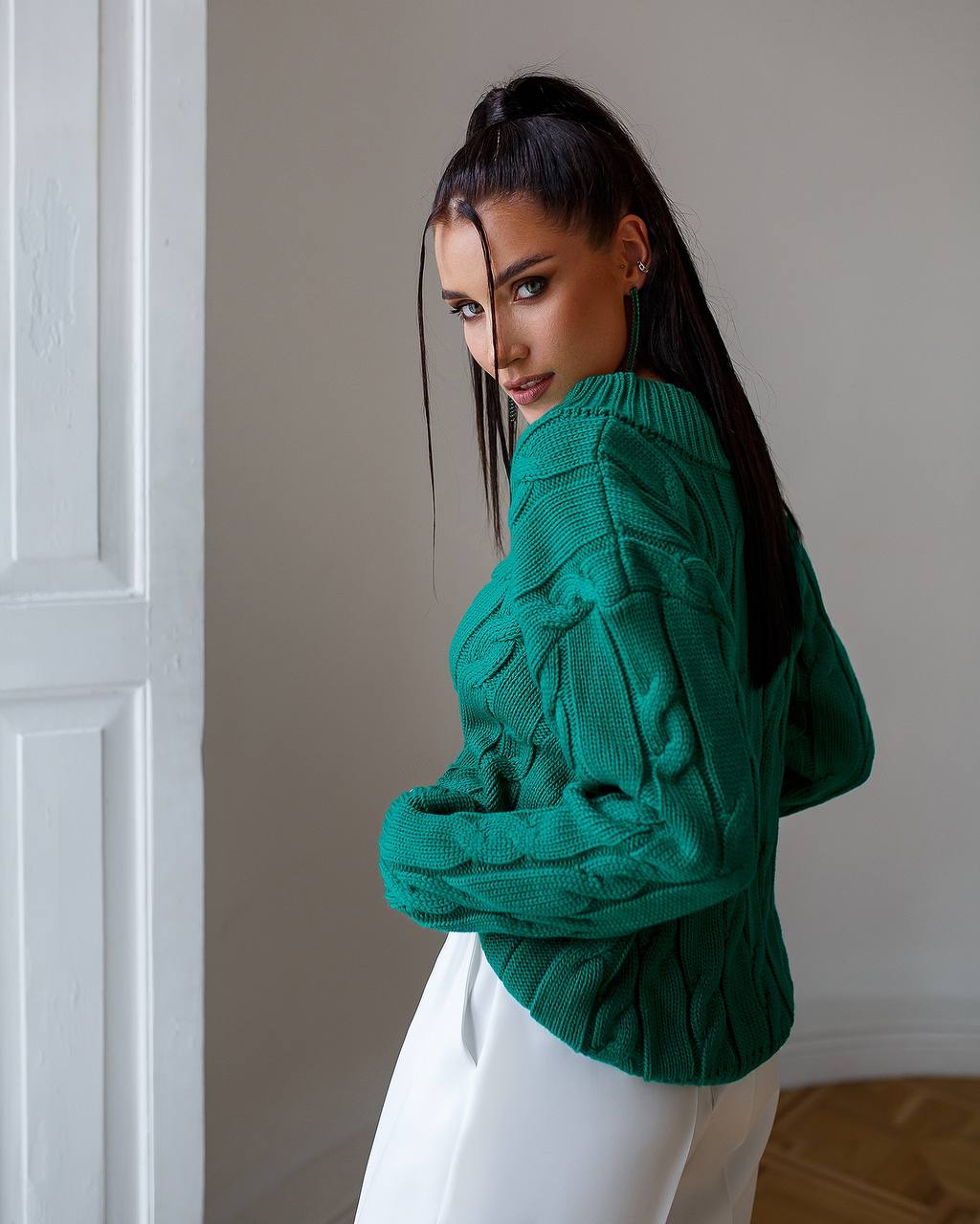 Woman wearing a green sweater against a neutral wall