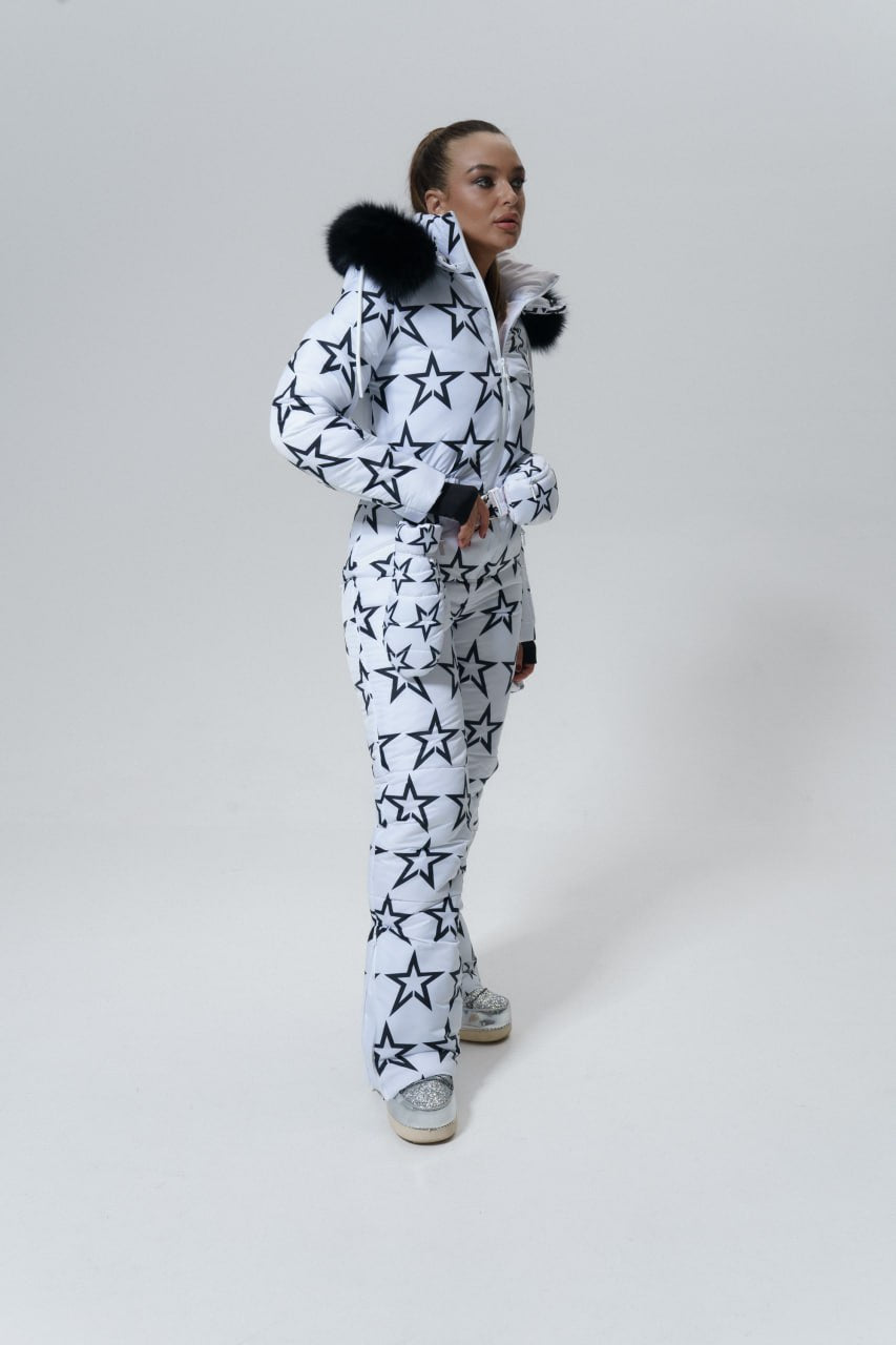 Person wearing a star-patterned snowsuit with fur-lined hood on a white background