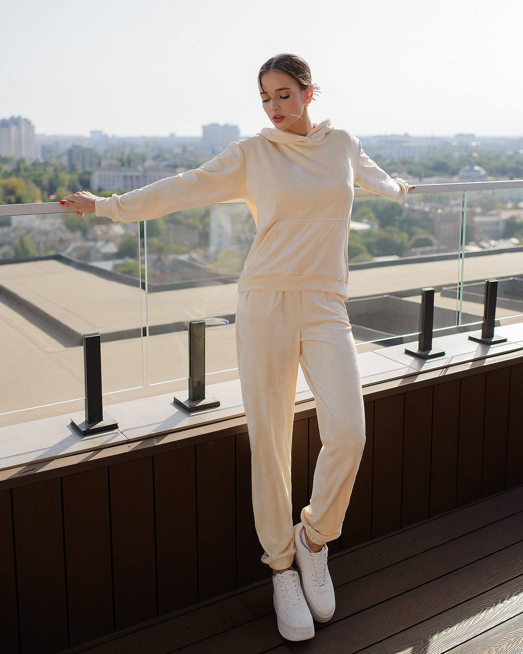 Woman in a white outfit standing on a rooftop with a cityscape in the background