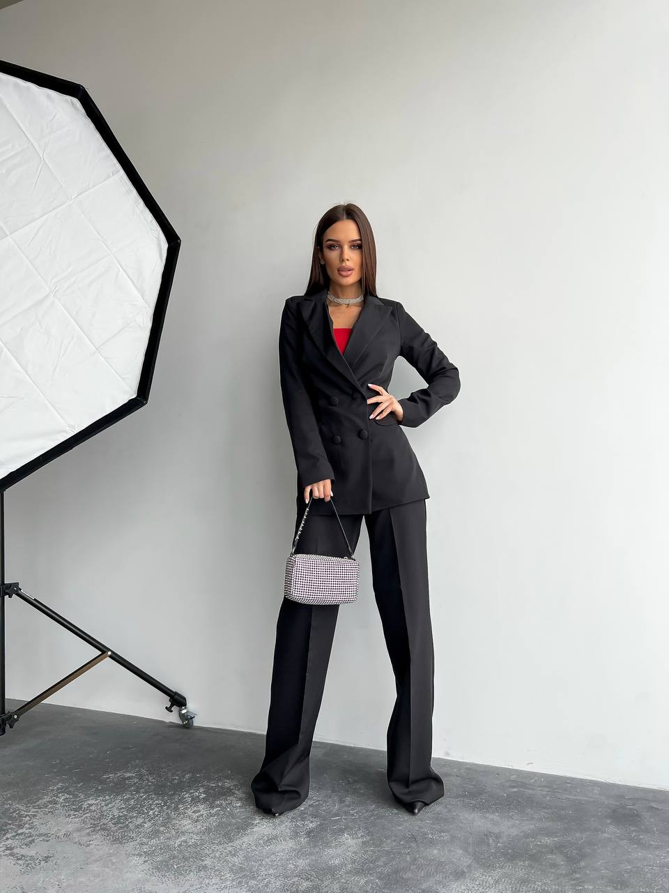 Woman in a black suit standing in a photo studio with lighting equipment.
