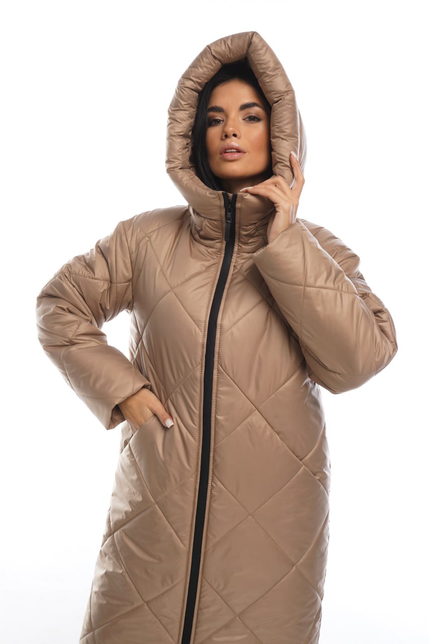 Woman wearing a beige quilted coat with a hood on a white background